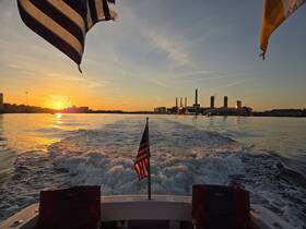 A stunning sunset view from the back of a boat, showcasing the tranquil waters and city skyline, perfect for evening cruises.
