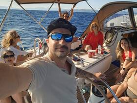 A joyful group enjoys a sailing adventure on the open sea, capturing memories with smiles and laughter. Perfect for family outings or group celebrations.