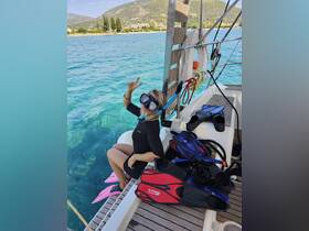 A woman prepares for snorkeling with fins and mask on a boat, showcasing the vibrant turquoise waters and scenic backdrop — perfect for adventure seekers.