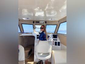 A woman smiles while seated at the helm of a boat, showcasing the stylish interior and modern controls — perfect for navigating the open waters.