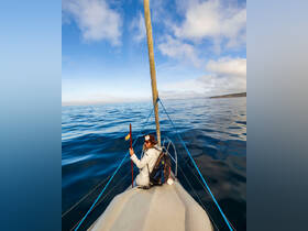 A woman enjoys a serene sailing experience on calm waters, showcasing the beauty of ocean adventures.