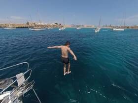 A young boy prepares to jump into the crystal-clear waters from a boat, capturing the thrill of summer adventures on the ocean.