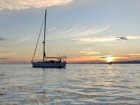 A serene sunset view of a sailboat anchored in calm waters, perfect for showcasing tranquil sailing experiences.