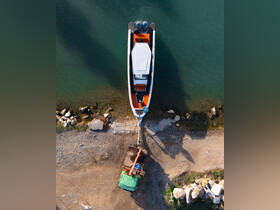 Aerial view of a boat docked at the shore, with a green vehicle preparing to launch it into the water. This scene captures the essence of boating preparation and outdoor adventure.