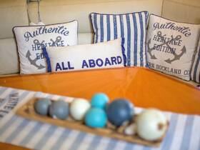 Cozy interior of a boat featuring decorative cushions and a stylish table setting, perfect for relaxing and enjoying time on the water.