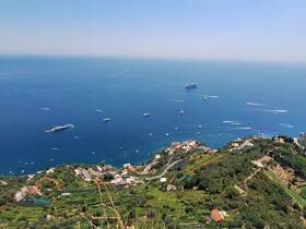 A stunning aerial view of the coastline featuring multiple yachts cruising in the vibrant blue waters, showcasing the beauty of the Mediterranean landscape.