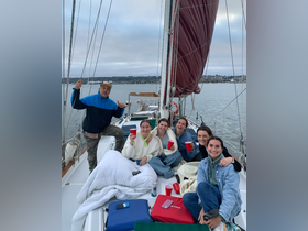 A lively group of friends enjoys drinks and laughter aboard a sailboat, capturing the essence of a fun sailing adventure on the water.