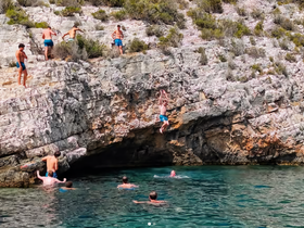 A group of friends enjoys a thrilling day of cliff jumping and swimming in crystal-clear waters, capturing the essence of summer adventure.