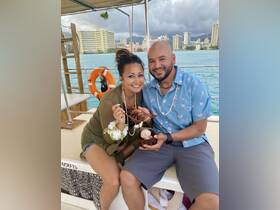 A happy couple enjoys a delightful moment on a boat, sharing food and smiles against a stunning ocean backdrop — perfect for romantic getaways or special celebrations.