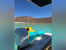 A person relaxes on a floating mat in crystal-clear waters, surrounded by stunning natural scenery — a perfect spot for a day of fun and relaxation on the water.
