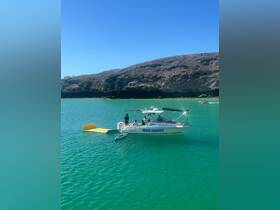 A group enjoys a day on the water aboard the 'Tres Mares' boat, with a kayak visible alongside, set against a stunning turquoise backdrop.