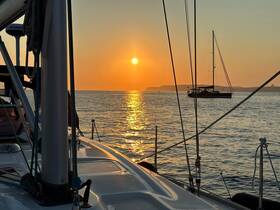 A serene sunset view from the deck of a sailboat, capturing the tranquil waters and another vessel in the distance — perfect for peaceful evening cruises.