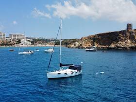 A picturesque view of a sailboat anchored in clear blue waters, surrounded by other vessels and a scenic coastline, perfect for showcasing boating adventures.