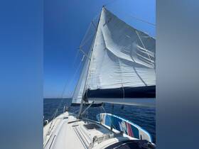 A close-up view of a sailboat's sail against a clear blue sky, showcasing the vessel's structure while underway on tranquil waters.