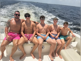 A group of five enjoying a sunny day on a boat, showcasing the fun and camaraderie of summer outings on the water.