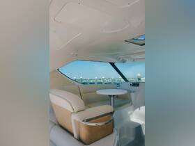 A stylish interior view of a boat cabin featuring comfortable seating and a small table, perfect for relaxing while enjoying the scenic marina views.