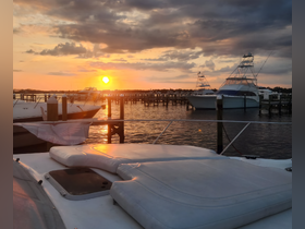 A serene sunset view from the deck of a yacht, showcasing the tranquil marina with boats docked in the background — perfect for evening relaxation.