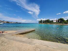 A scenic view of a vibrant beach with people swimming in crystal-clear waters, perfect for a relaxing day by the coast.
