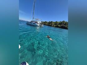 A swimmer enjoys the crystal-clear waters near a catamaran, showcasing the perfect summer day on the water.
