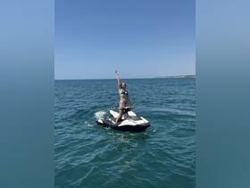 A woman joyfully rides a jet ski in clear waters, showcasing the thrill of water sports and summer fun.