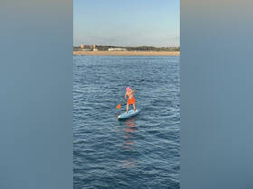 A person paddleboards in calm waters near a sandy beach, showcasing a fun and active day on the water.