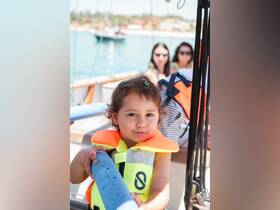 A young girl in a bright life jacket smiles while aboard a boat, capturing the joy of family adventures on the water.