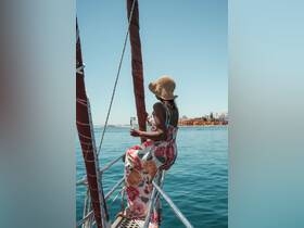 A woman enjoys a refreshing drink while relaxing on the deck of a yacht, capturing the essence of leisure and celebration on the water.