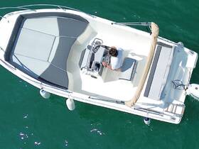 An aerial view of a person at the helm of a sleek boat, showcasing the modern interior design and seating arrangement — perfect for a day on the water.