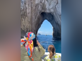 Guests enjoy a scenic boat ride through a stunning rock arch, capturing the beauty of the ocean and surrounding landscape — a perfect highlight of their adventure.