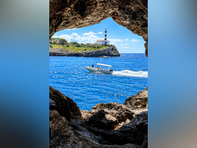 A scenic view of a boat navigating past a picturesque lighthouse, framed by rocky outcrops — a perfect representation of coastal adventures.