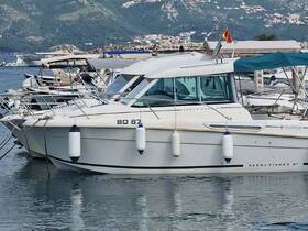 A sleek Merry Fisher boat docked in a marina, showcasing its elegant design against a scenic backdrop of hills and other vessels.
