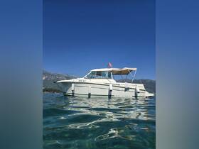 A stunning view of a Merry Fisher boat anchored in crystal-clear waters, showcasing its sleek design against a backdrop of blue skies and mountains.