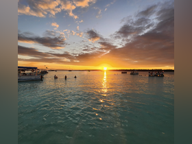 A stunning sunset view with people enjoying the water, creating a picturesque scene perfect for beach outings and evening gatherings.