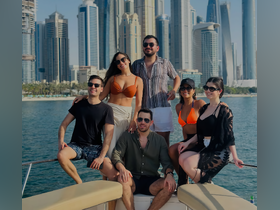 A vibrant group of friends poses on the deck of a yacht with a stunning city skyline in the background, perfect for capturing memorable moments during a day on the water.