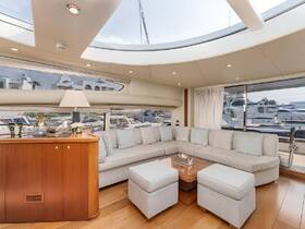 A spacious and elegantly designed lounge area inside a yacht, featuring comfortable seating and large windows that offer views of the marina.