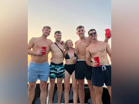 A group of friends celebrates together on a boat at sunset, enjoying drinks and good company — perfect for summer parties and memorable outings on the water.