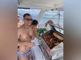 A cheerful guest barbecues a variety of meats on the grill aboard a boat, showcasing a perfect setup for a fun day on the water with delicious food.