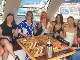 A group of friends enjoys a delightful spread of food and cocktails aboard a boat, perfect for celebrations and gatherings on the water.
