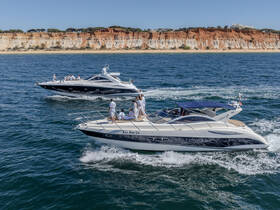 Two luxurious yachts cruise along a stunning coastline, showcasing a lively group enjoying their time on the water — perfect for summer adventures and celebrations.
