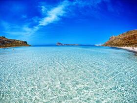 A stunning view of a serene beach with crystal-clear waters and a picturesque coastline, perfect for a relaxing day in the sun.