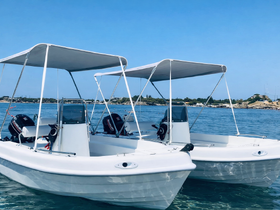 Two sleek speedboats with canopies are anchored in calm waters, showcasing their modern design against a clear blue sky.