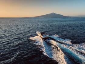 A stunning aerial view of a speedboat cruising through the open water, with a picturesque mountain backdrop, perfect for showcasing the thrill of boating adventures.