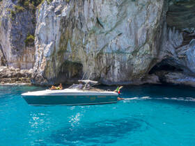 A stunning view of a boat cruising near a rocky coastline with a cave, showcasing a perfect day on the water. Ideal for exploring beautiful destinations and enjoying the sun.