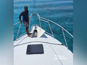 A man stands at the bow of a boat, surrounded by stunningly clear turquoise waters, showcasing the beauty of a day on the ocean.