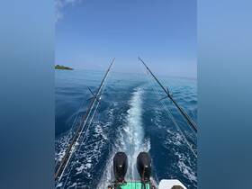A view from the back of a fishing boat cruising through clear blue waters, showcasing the vessel's twin engines and fishing rods, perfect for a day of adventure on the sea.