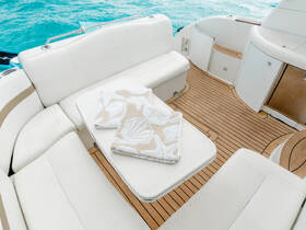 A cozy interior view of a boat's lounge area featuring comfortable seating and decorative towels, perfect for relaxing on the water.