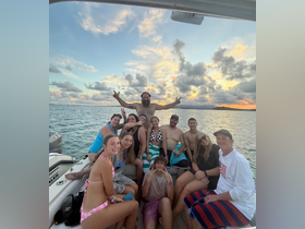 A lively group of friends enjoys a sunset celebration on a boat, capturing the joy of their day on the water.