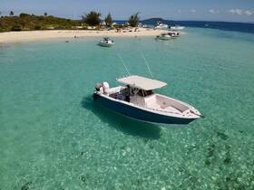 A stunning aerial view of a boat anchored in crystal-clear waters, surrounded by a picturesque beach and lush greenery, perfect for exploring tropical destinations.