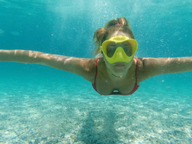 A swimmer enjoys snorkeling in crystal-clear waters, showcasing the vibrant underwater experience — perfect for adventure seekers.