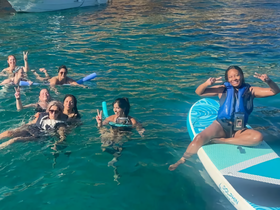 A lively group enjoys a fun day in the water, swimming and paddleboarding, showcasing the perfect atmosphere for a memorable boating experience.